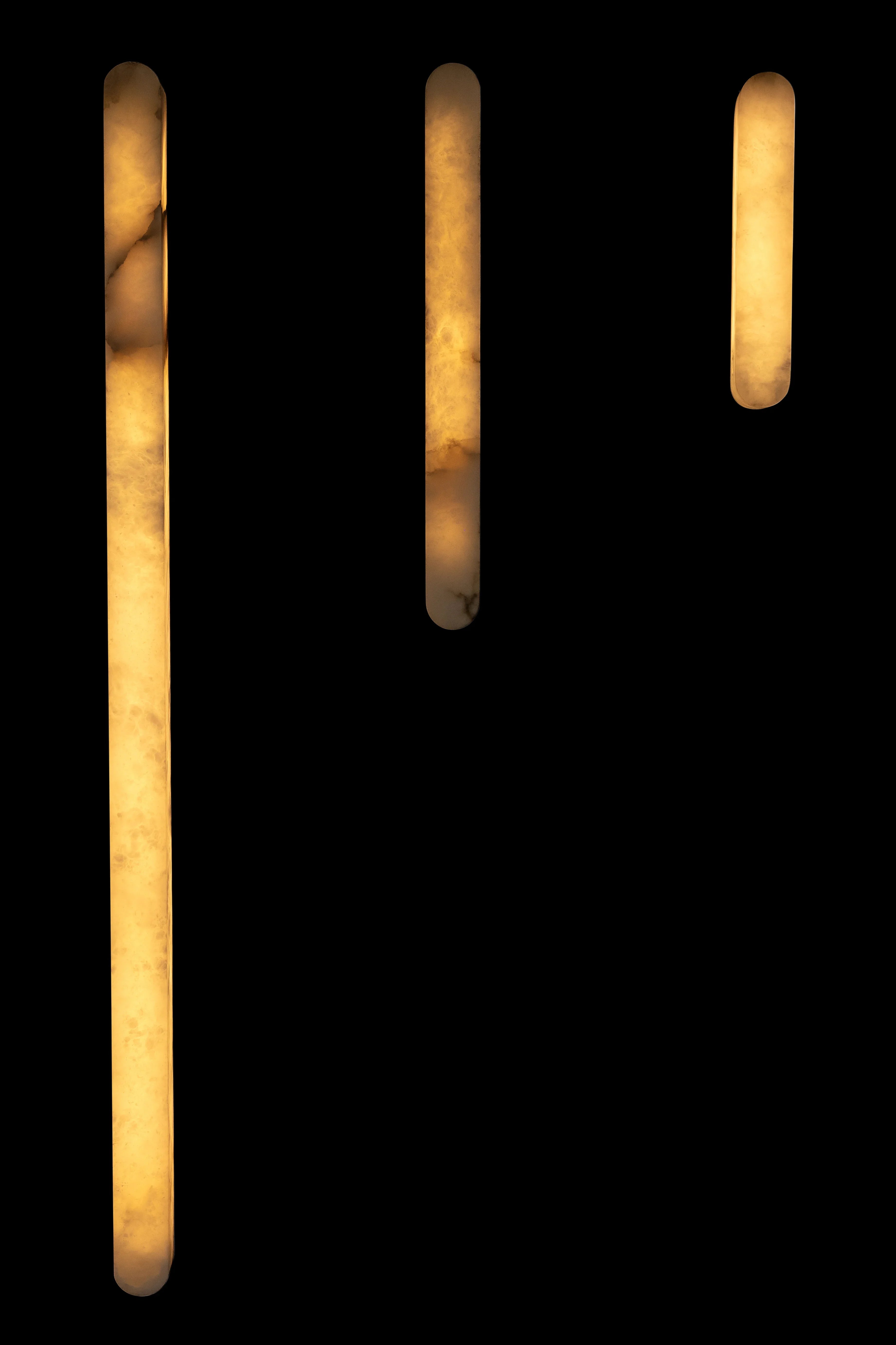 Modern luxury wall sconces with warm marble-effect diffusers against black background