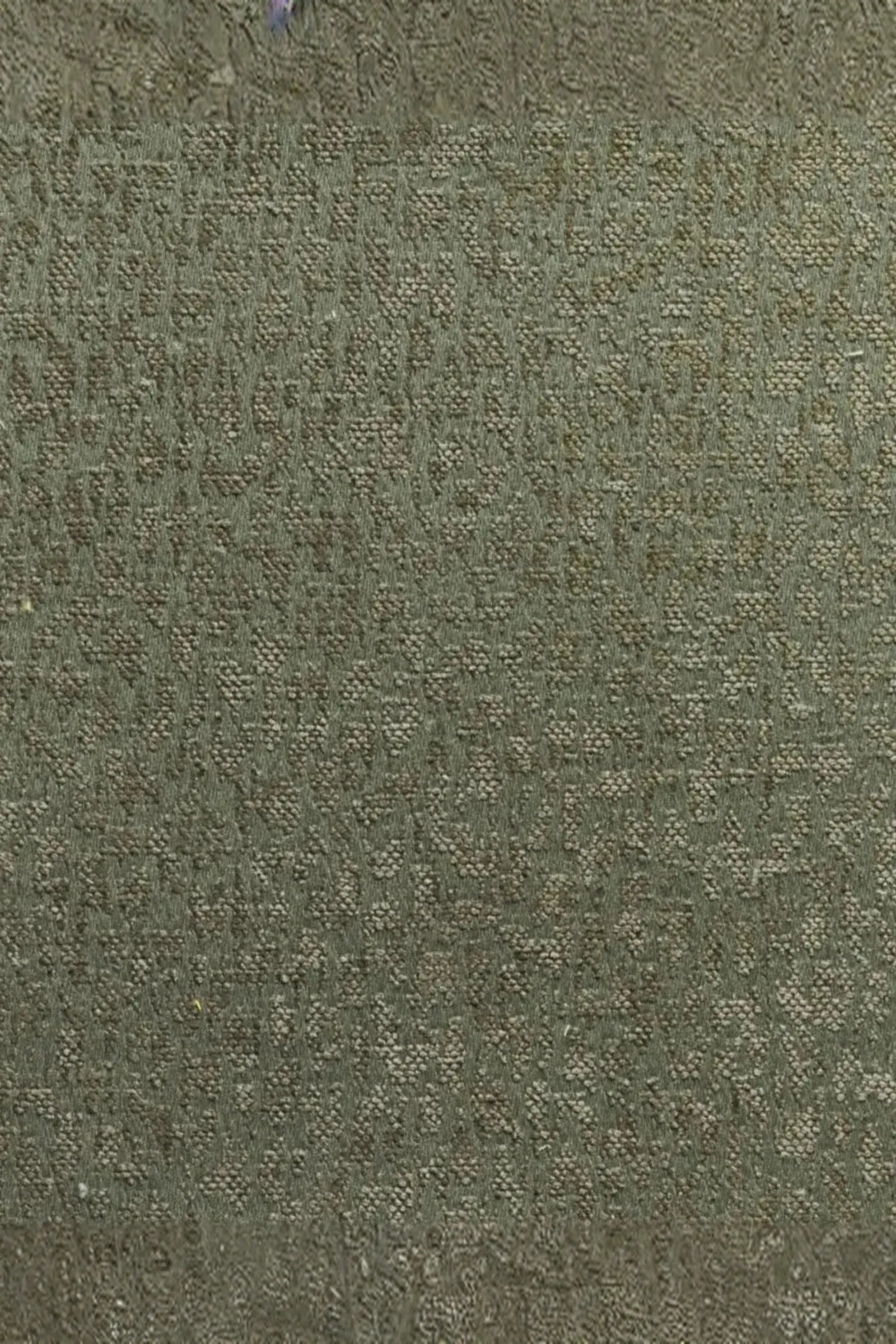 Close-up of textured green luxury upholstery fabric with subtle woven pattern.