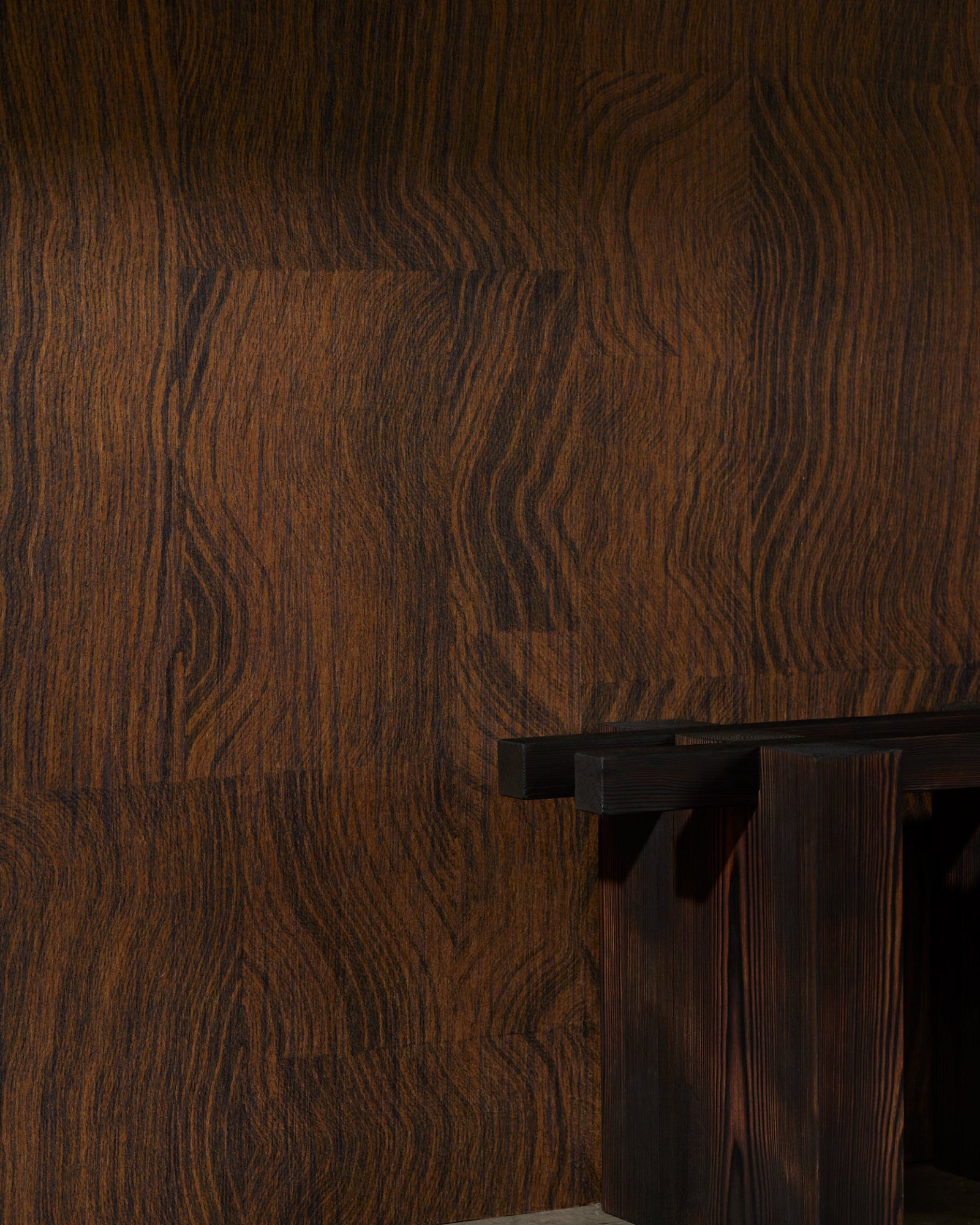 Minimalist dark wood console table against a textured wood-grain wall in luxury interior
