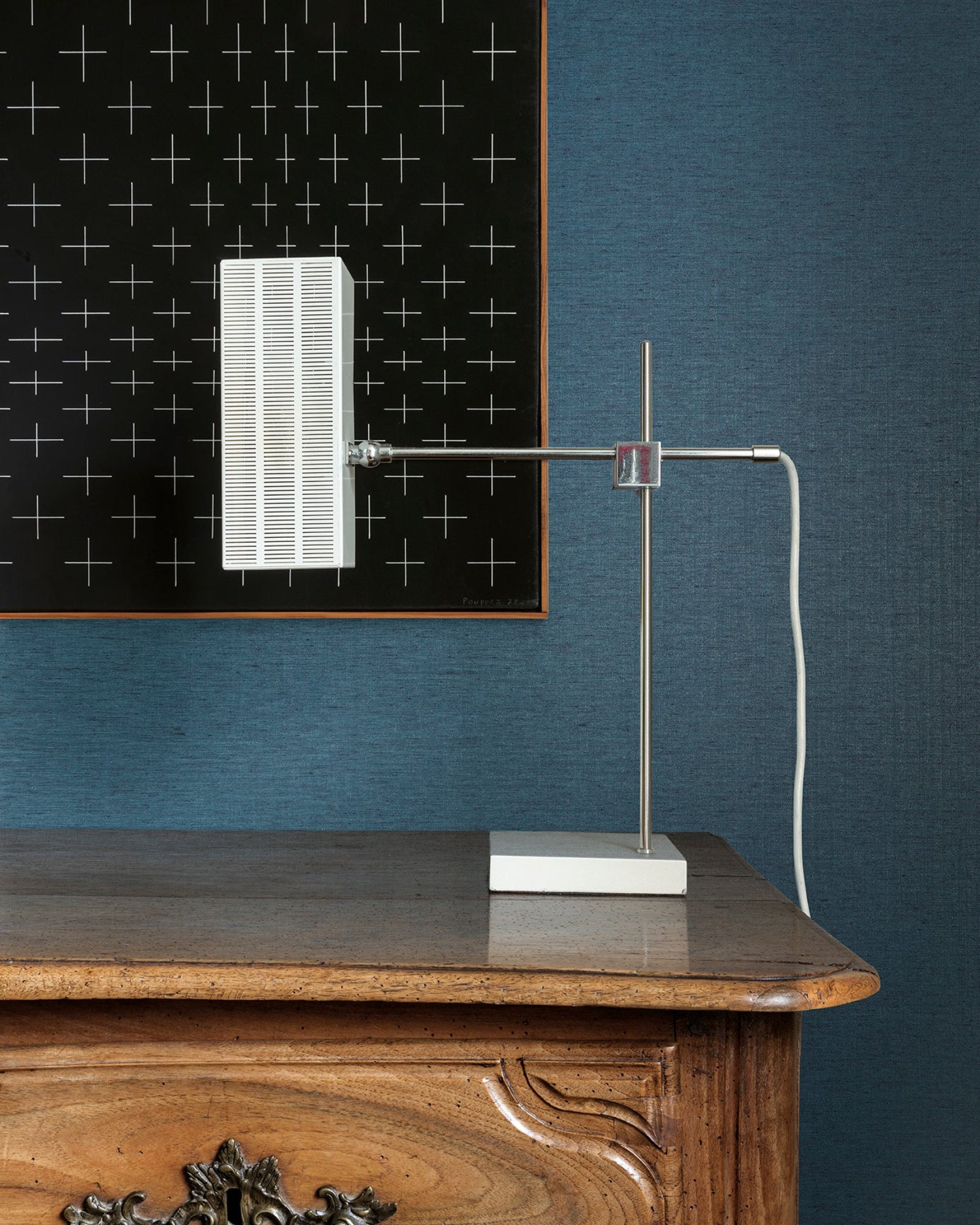Modern table lamp with rectangular white shade on a wooden desk against blue wall