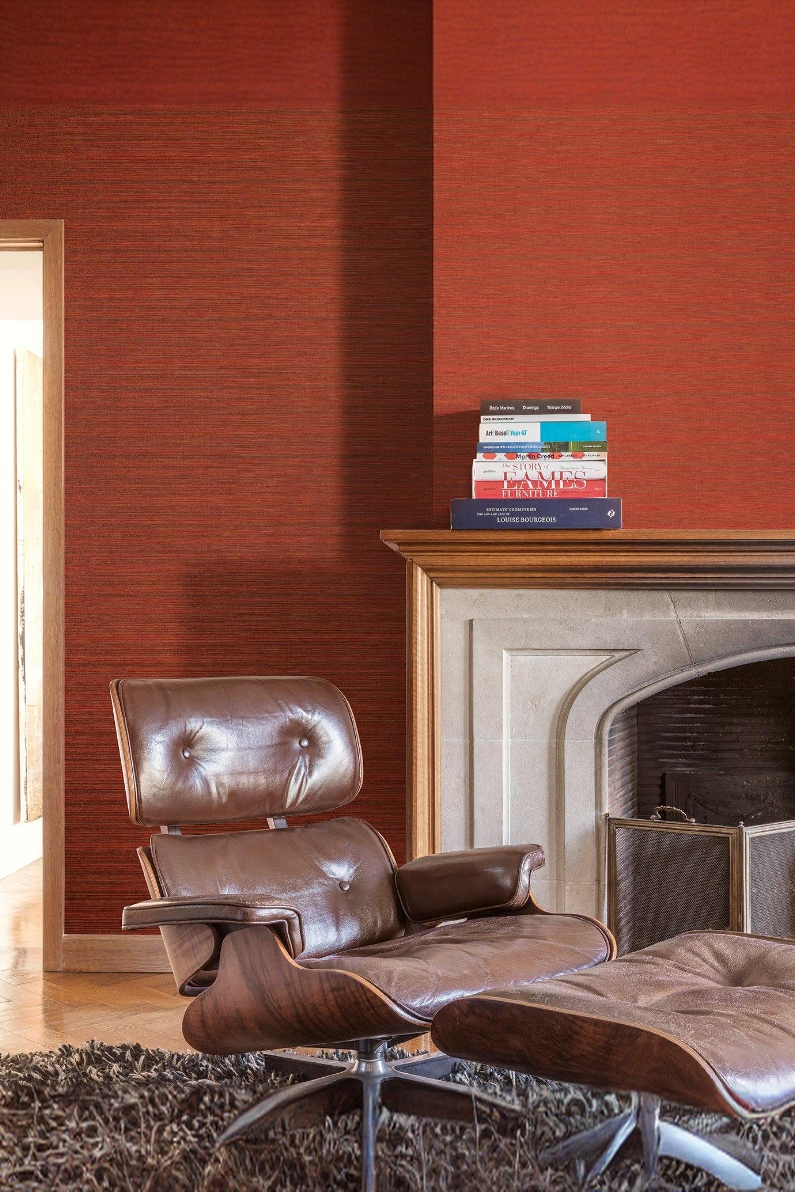 Luxury interior with brown leather lounge chair, red textured wall, and modern fireplace.
