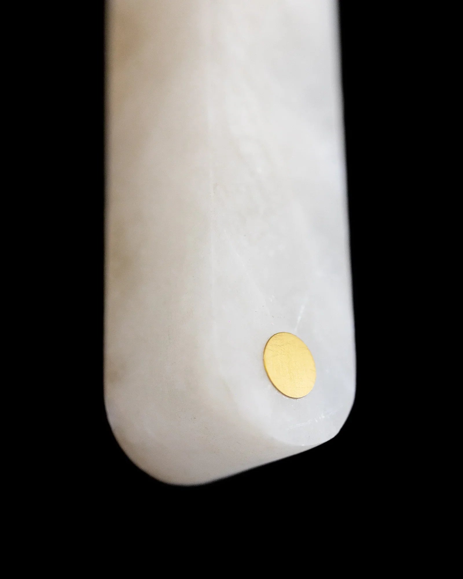 Close-up of a white marble object with a gold circular accent on a black background