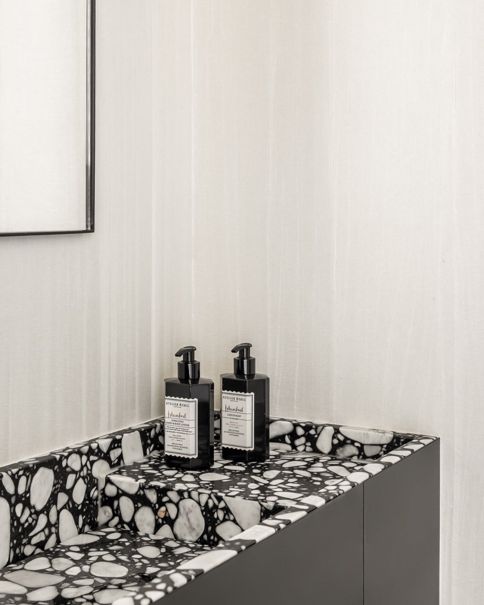 Luxury bathroom with black and white terrazzo sink and soap dispensers on modern vanity