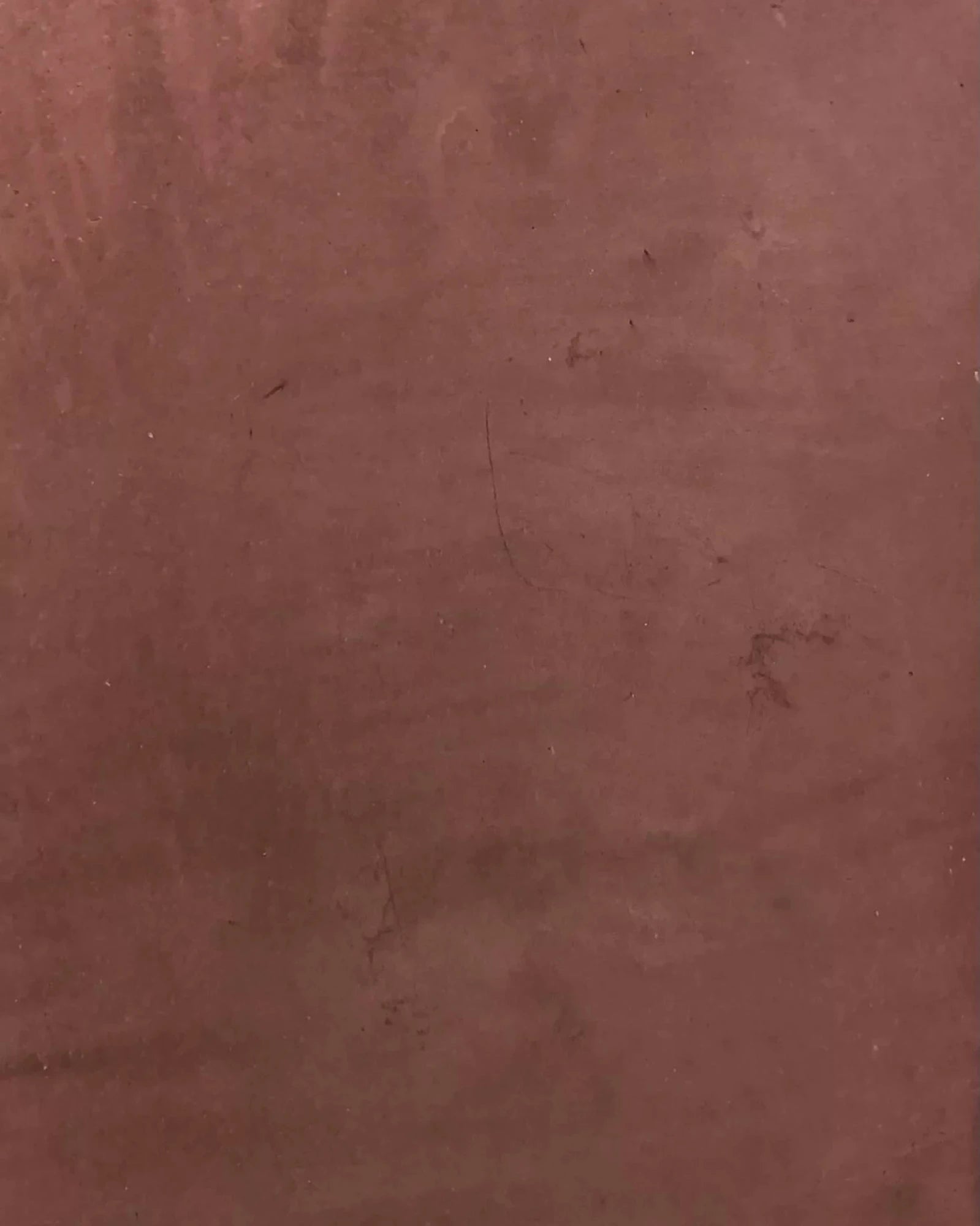 Textured reddish-brown plaster wall surface detail, suitable for luxury interiors.