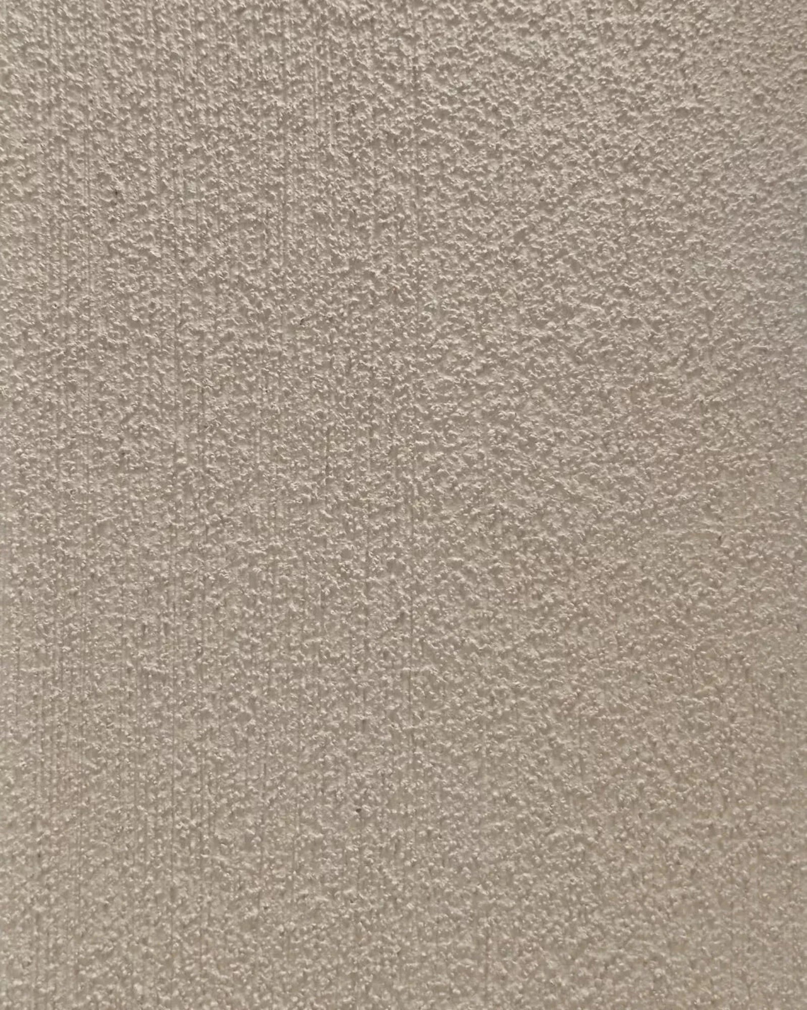 beige textured wall surface with subtle vertical lines and rough plaster finish