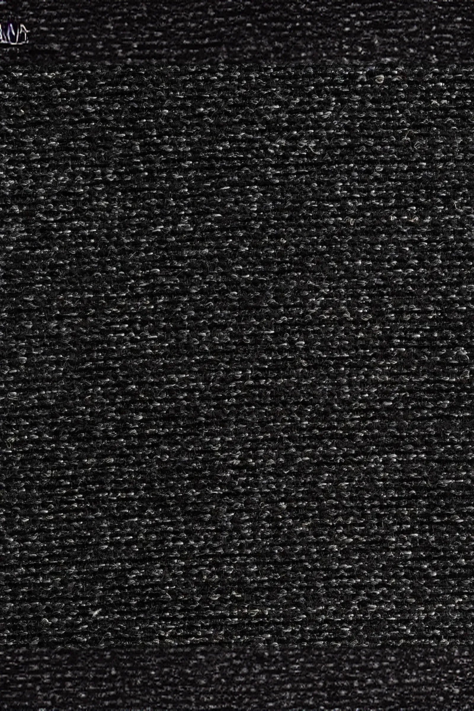 Close-up of dark textured fabric upholstery, showing woven charcoal black pattern