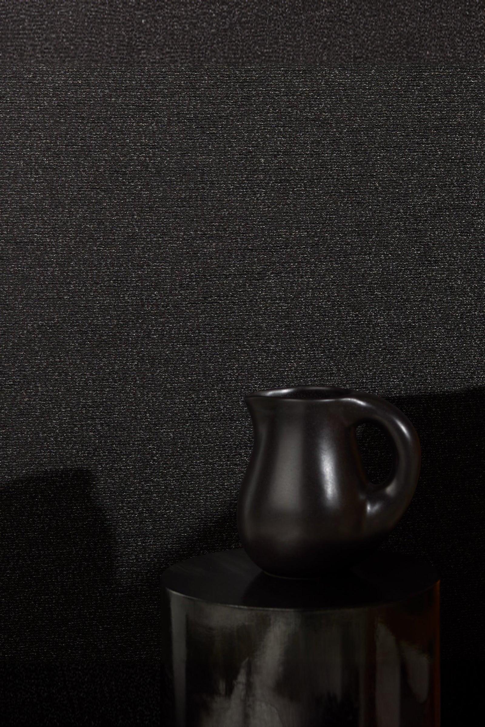 Matte black ceramic pitcher on a dark textured surface, modern luxury home decor