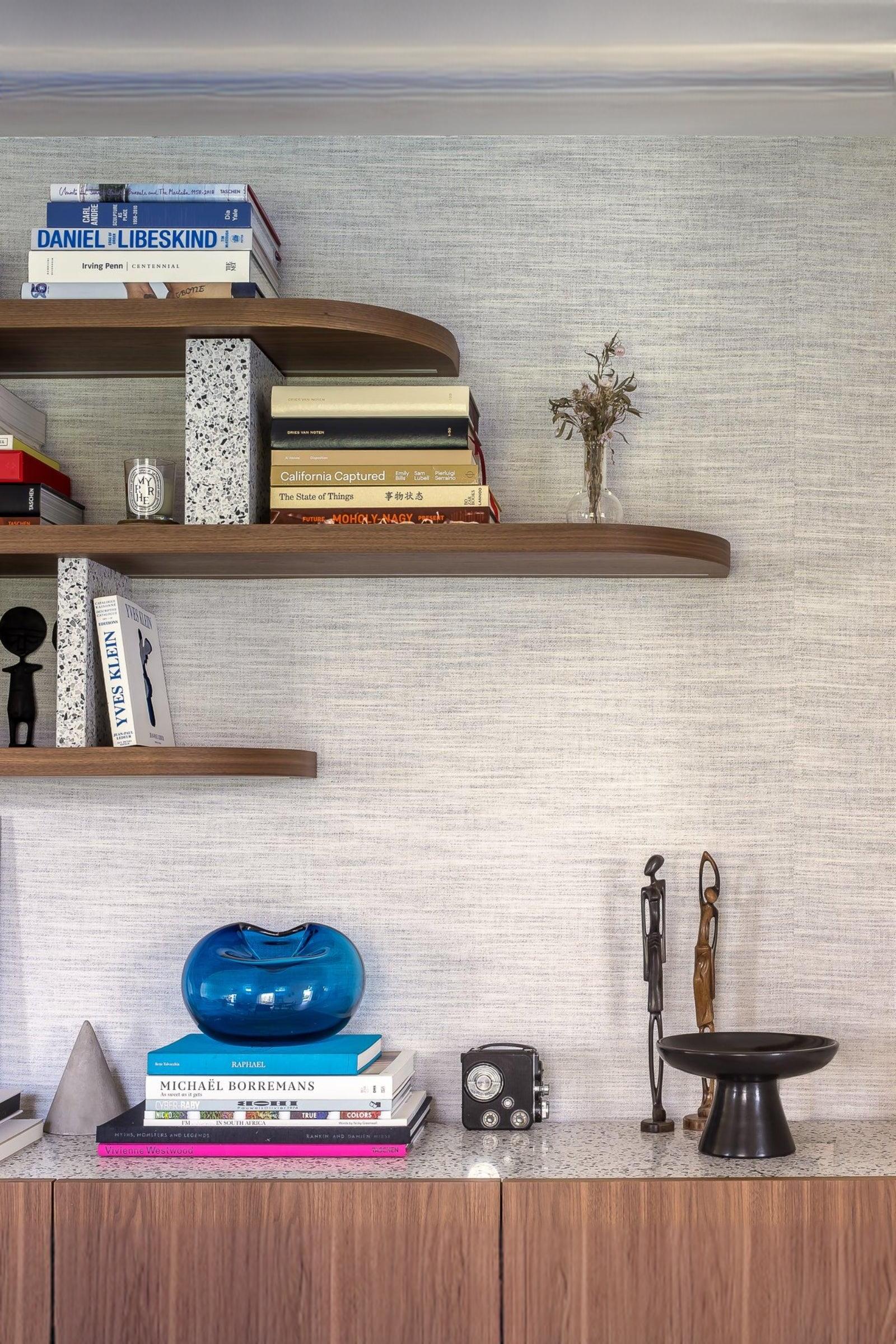 Modern luxury interior shelf with art books, blue glass vase, camera, and sculptural decor