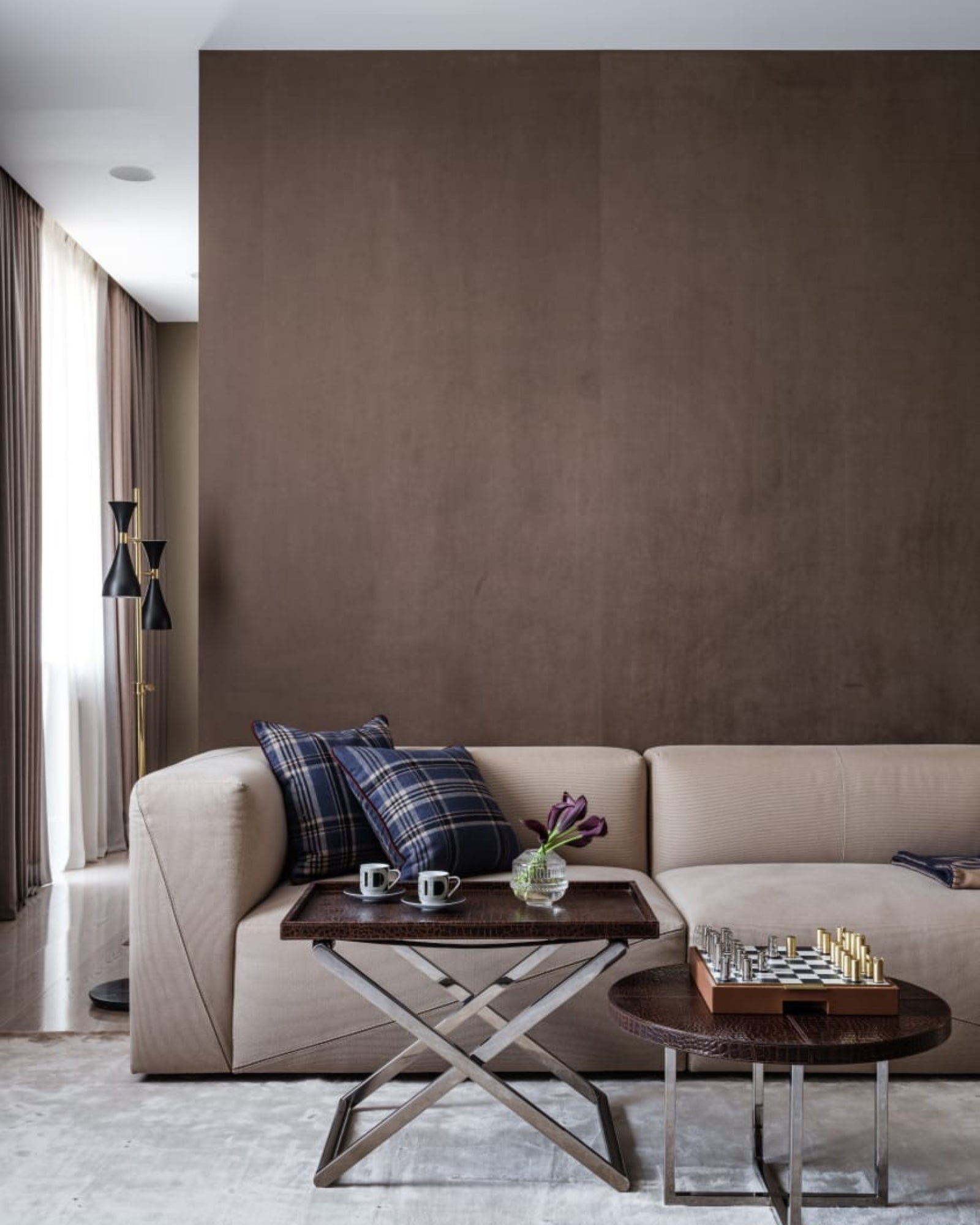 Luxury modern living room with beige suede sofa, plaid pillows, coffee table, and chess set.