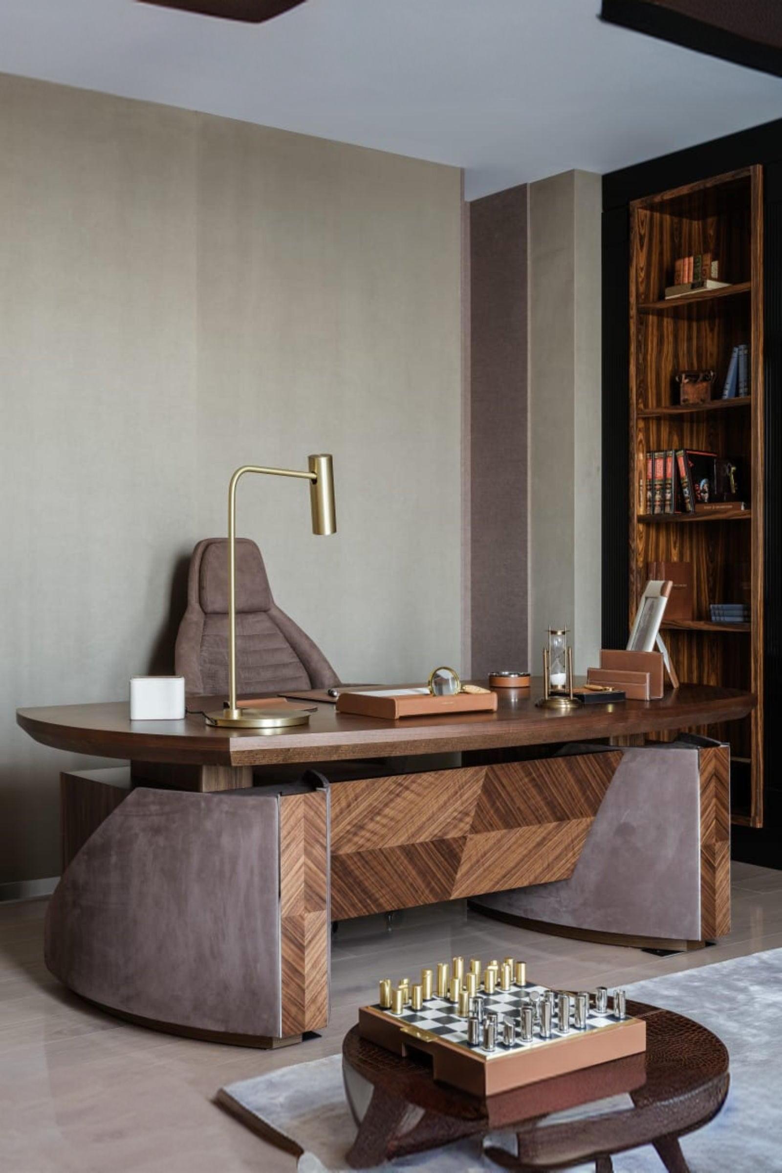 Luxury modern office with geometric wood desk, suede chair, gold lamp, and built-in bookshelf