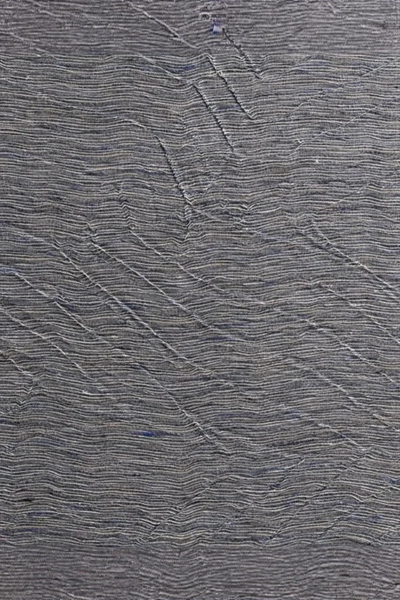 Close-up of textured grey woven fabric with organic, sculpted linear patterns