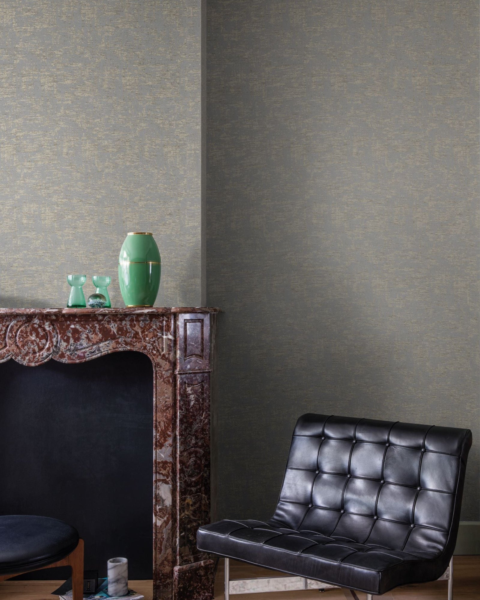 Modern luxury interior with tufted black leather chair, marble fireplace, decorative vases, and textured wallpaper.
