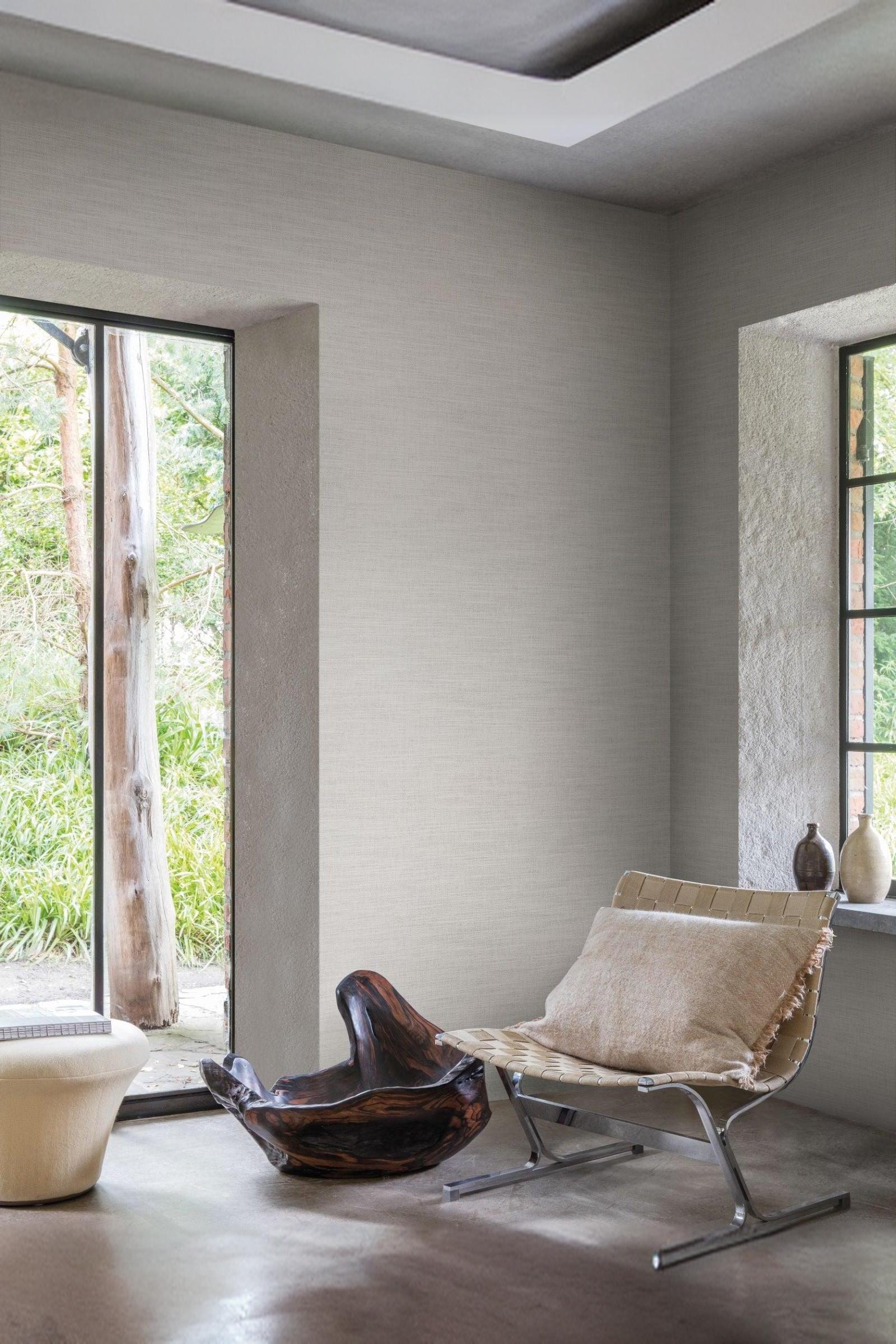 Modern luxury interior lounge with a woven chair, neutral wall, and large windows