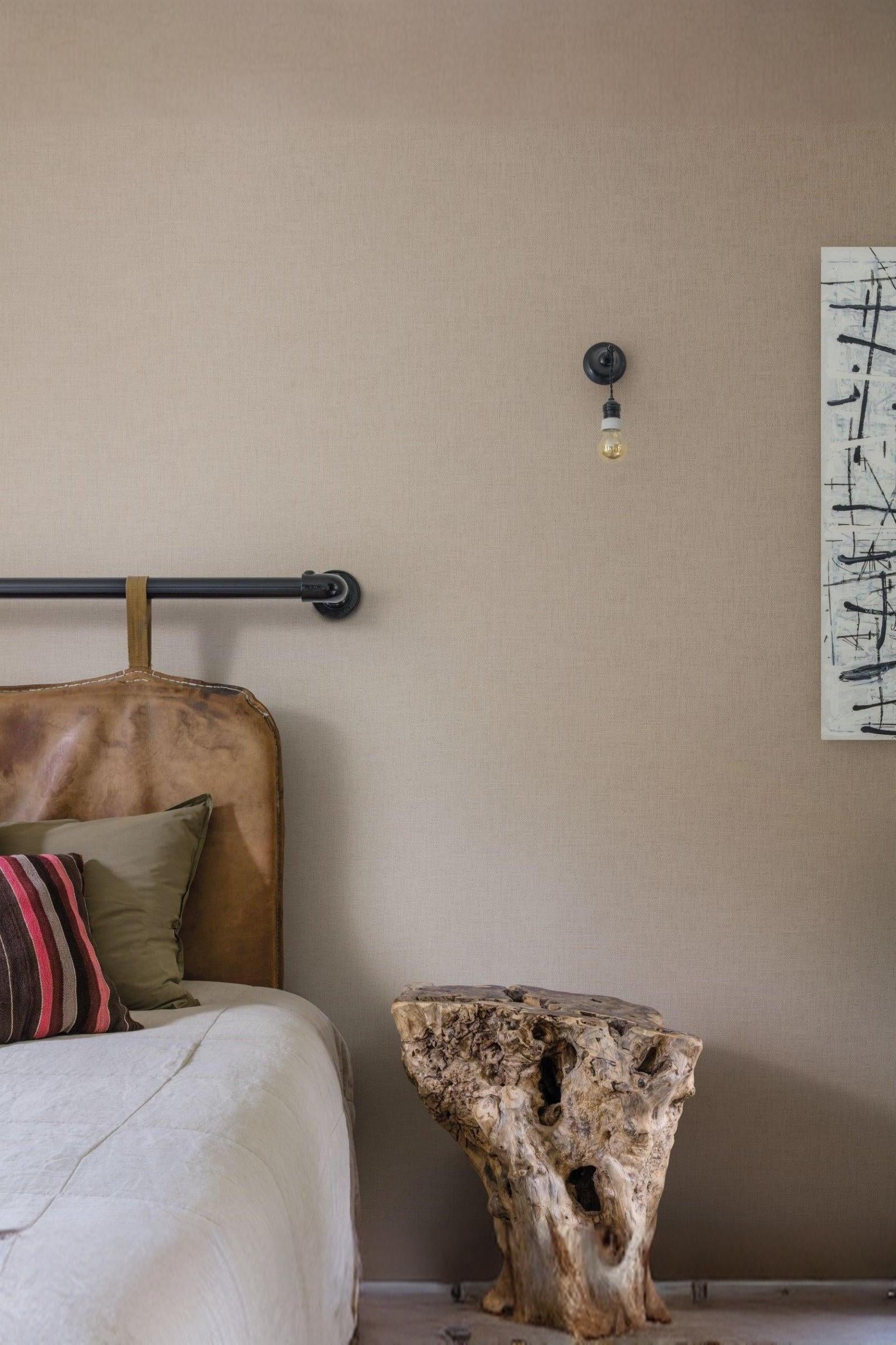 Luxury bedroom with leather headboard, rustic wood side table, and modern wall light