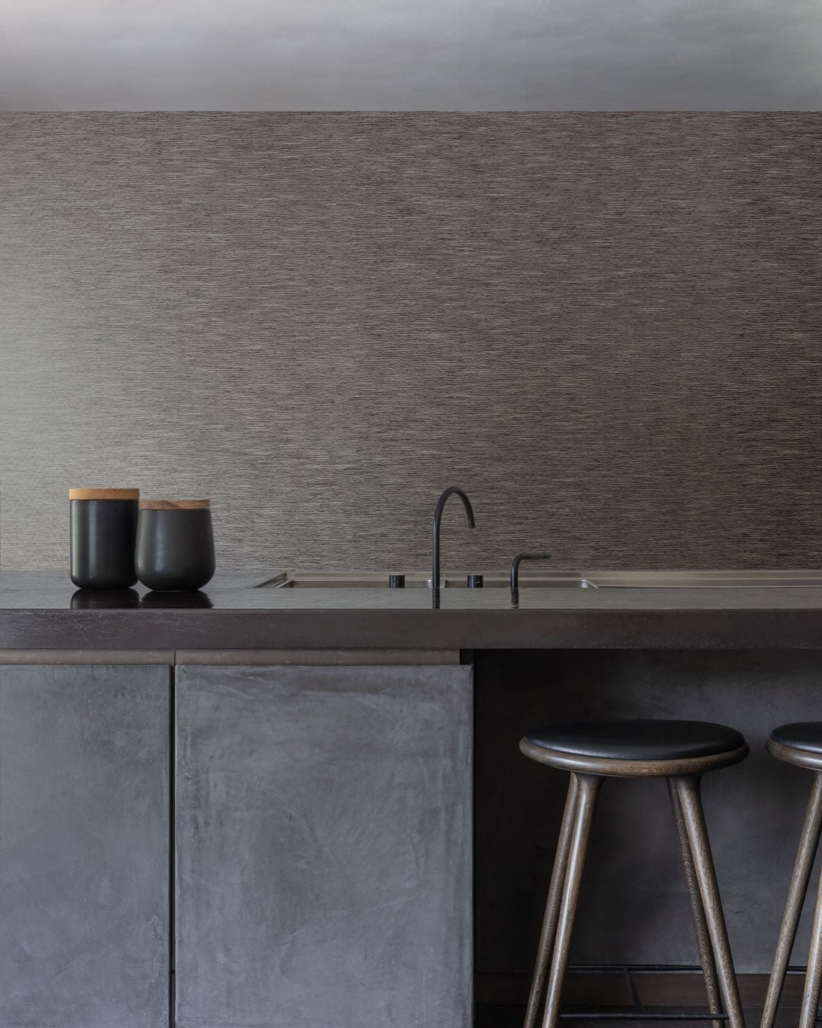 Modern luxury kitchen with minimalist dark island, sleek black faucet, and two wooden stools