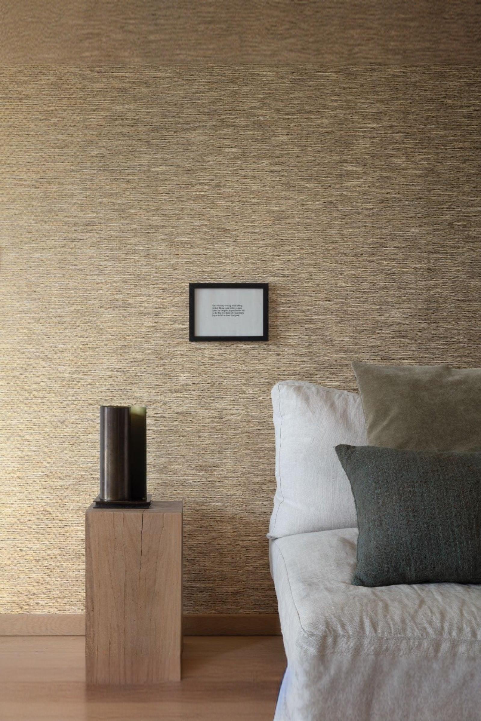 Modern luxury living room corner with textured beige wall, grey sofa, velvet pillows, and minimalist wood side table with dark decor accent.