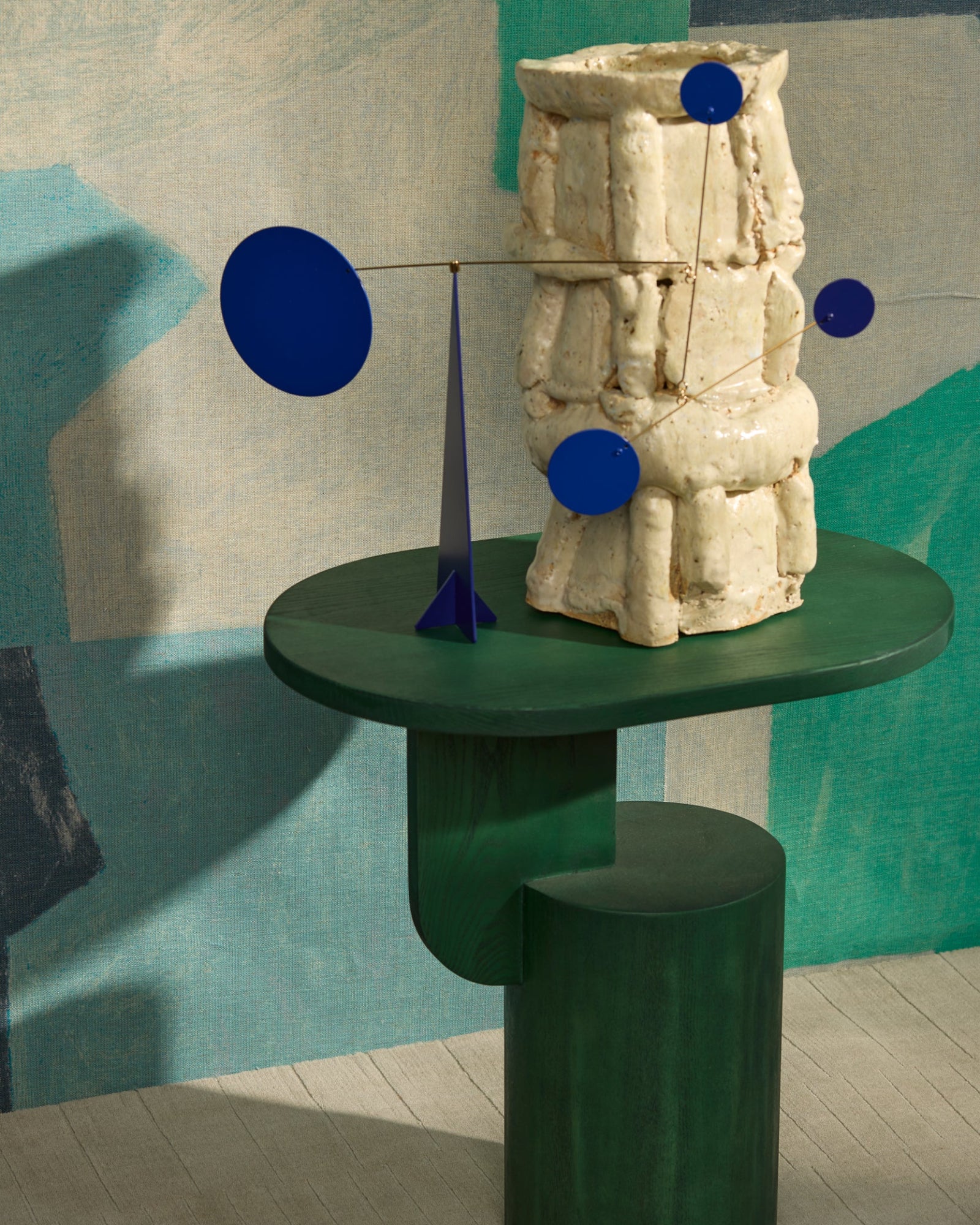 Modern green table with abstract ceramic vase and blue sculpture in a stylish interior