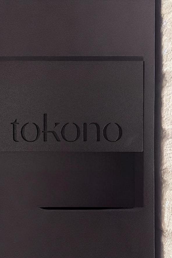Close-up of sleek black metal panel with 'tokono' text engraved, modern luxury interior finish