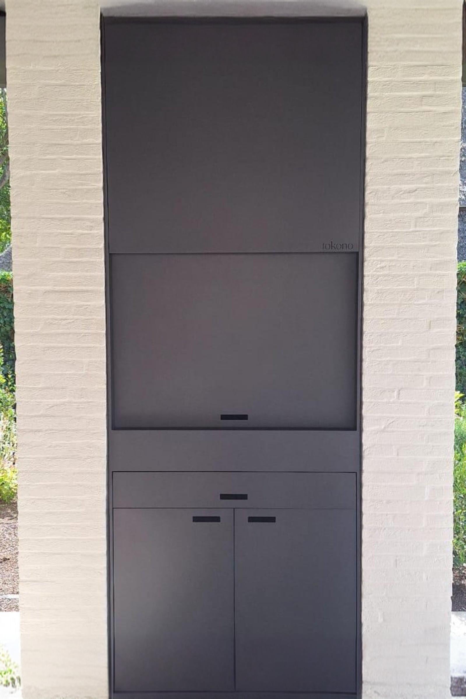Modern built-in outdoor fireplace with sleek black paneling set in a white brick wall.