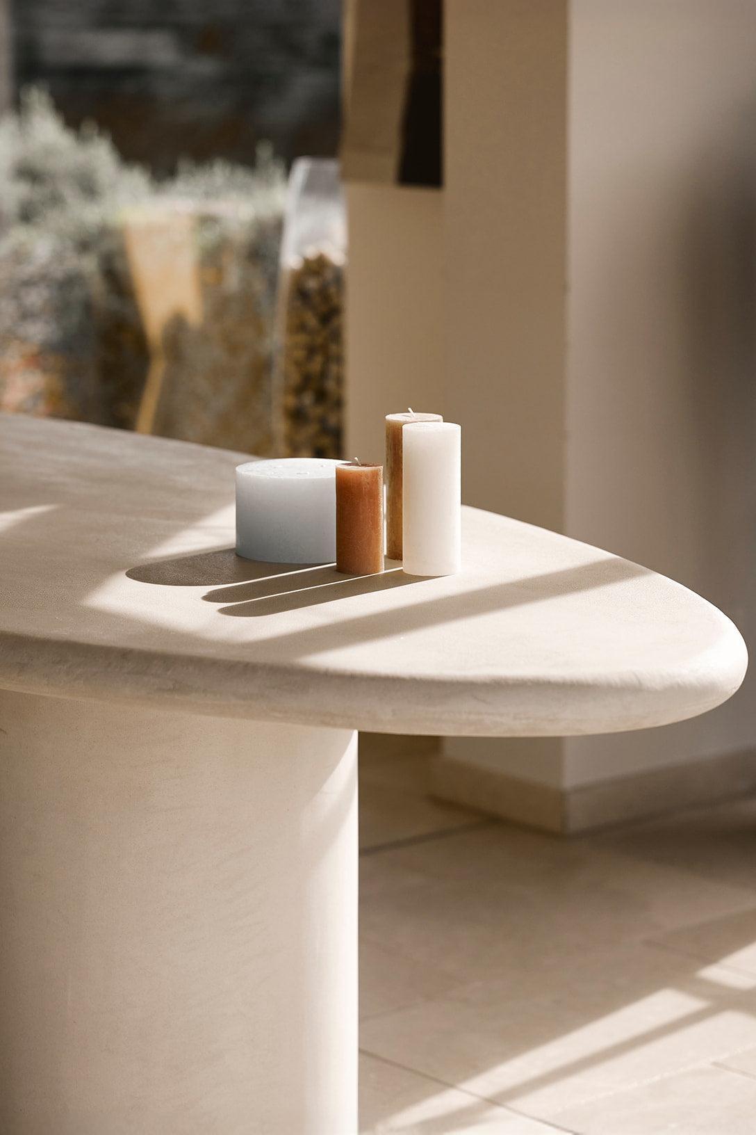 Minimalist high-end interior with natural light, round stone table, and decorative candles