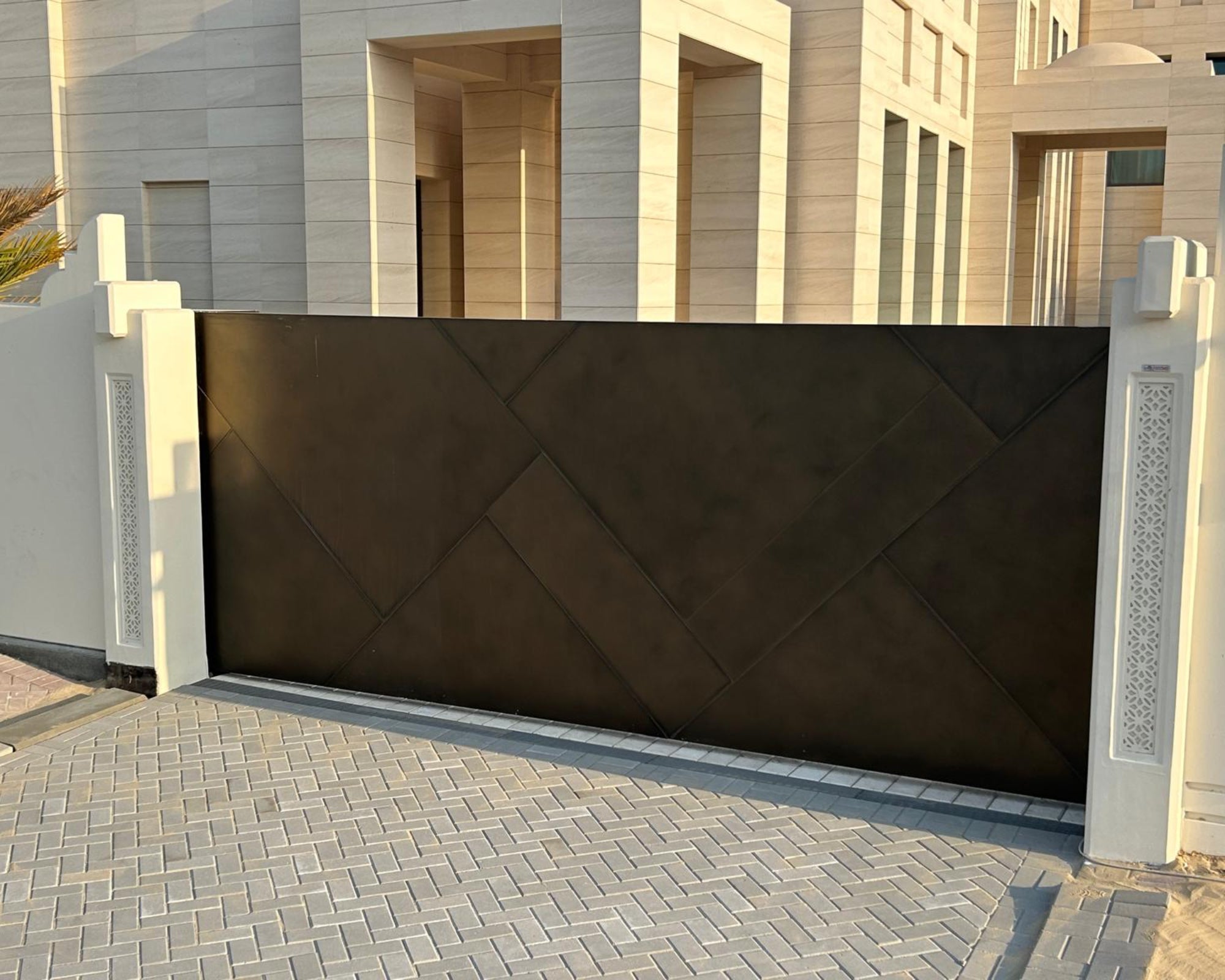 Modern luxury villa entrance with large geometric metal gate and stone exterior