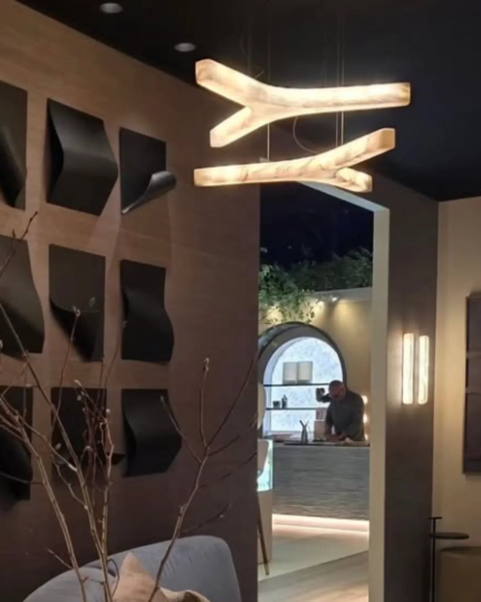 Modern luxury interior with sculptural pendant light, geometric wall art, and open kitchen view