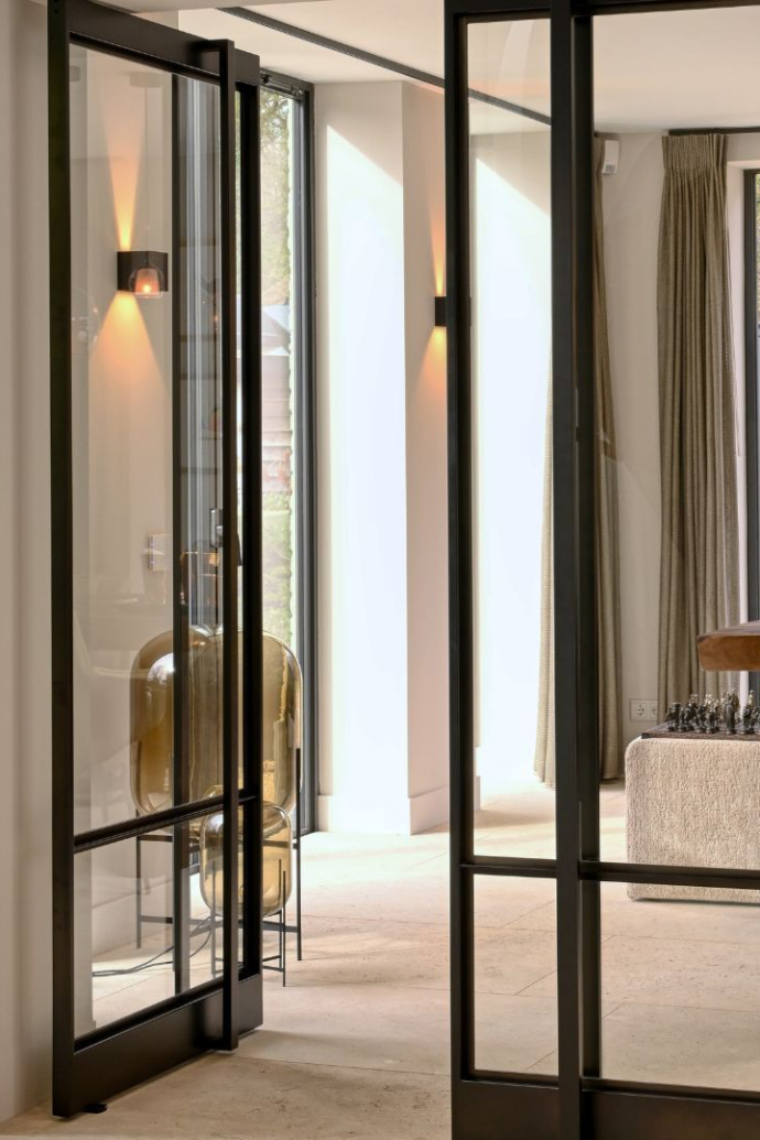 Slim black metal doors by Belgian atelier Mform connecting two calm living spaces 