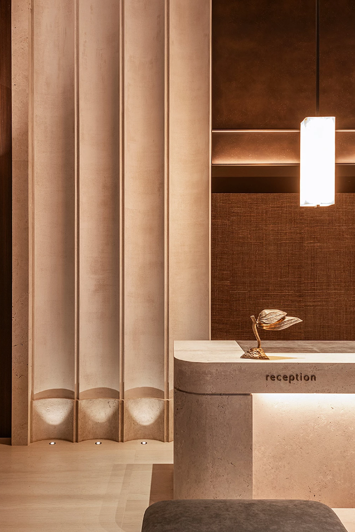 Boutique hospitality reception with warm stone counter and soft textile wall panels